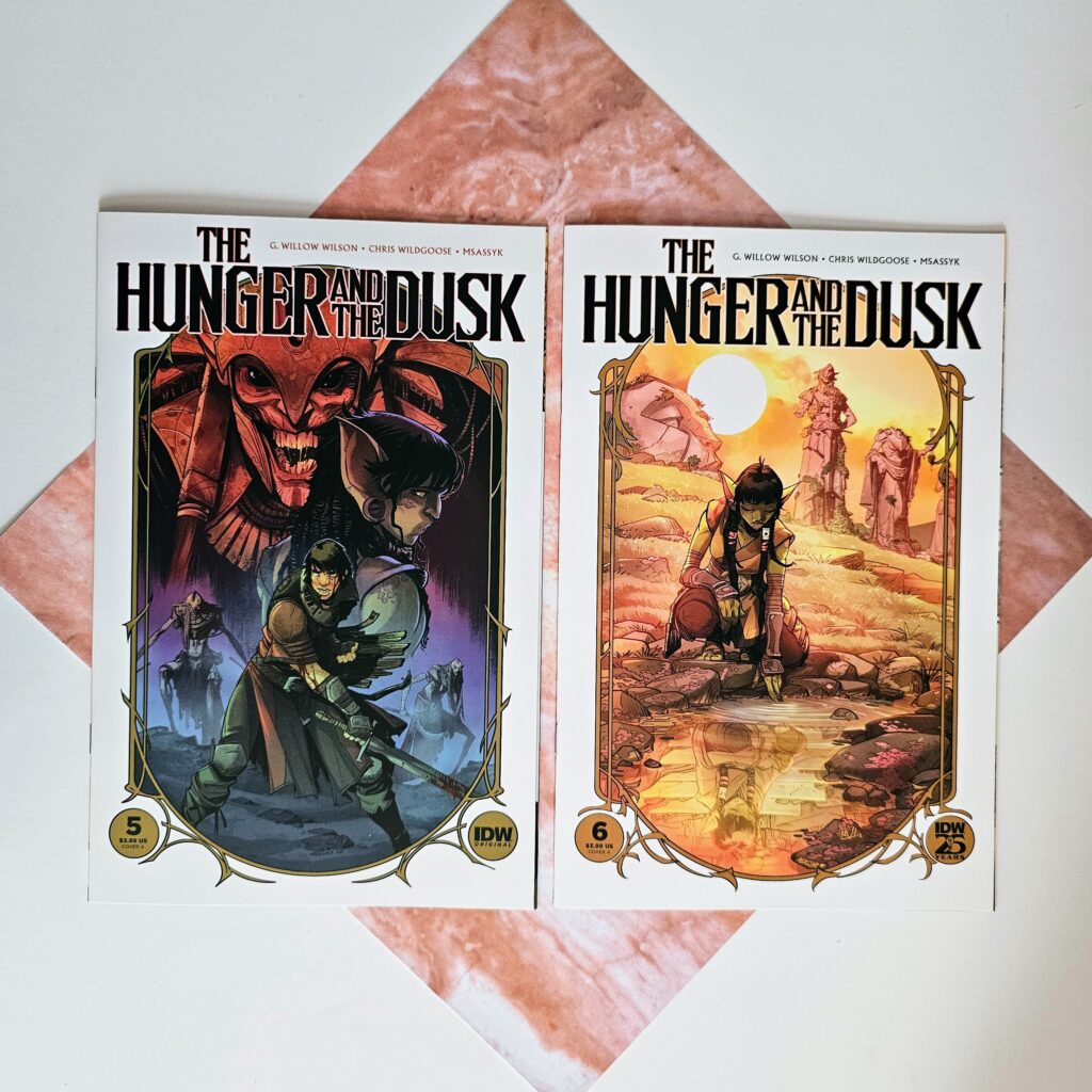 Issues 5 and 6 of The Hunger and The Dusk laying on a square piece of paper that looks like pink marble.